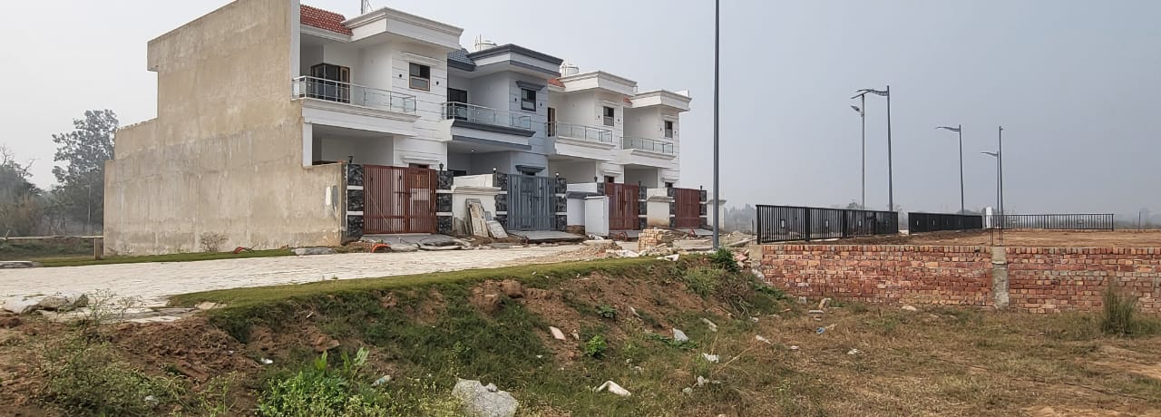 Newly built residential villas with open plots and streetlights in a developing area.
